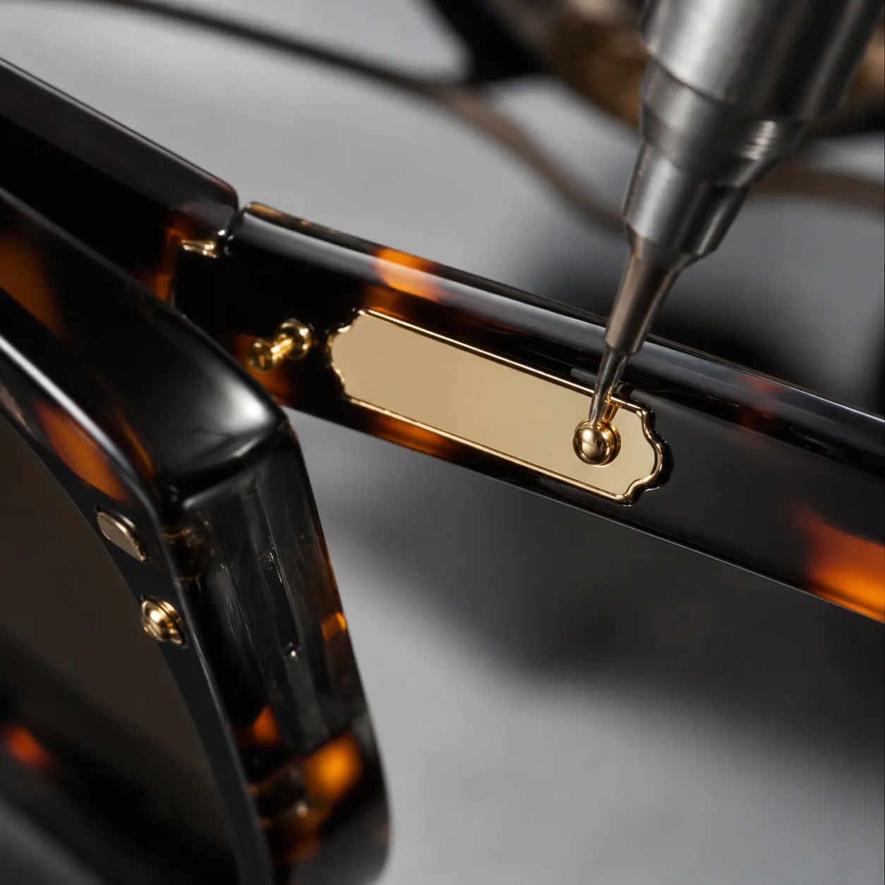 Metal logo plate attached to sunglasses temple